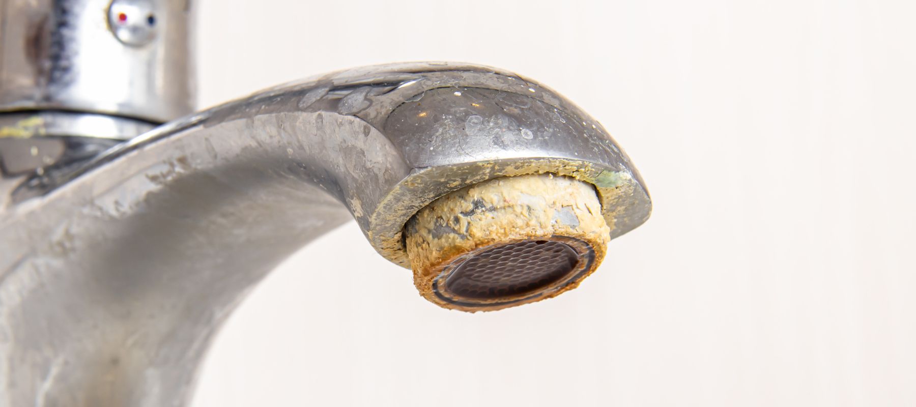 Close-up of a bathroom faucet heavily coated with crusty white and yellow hard water mineral deposits