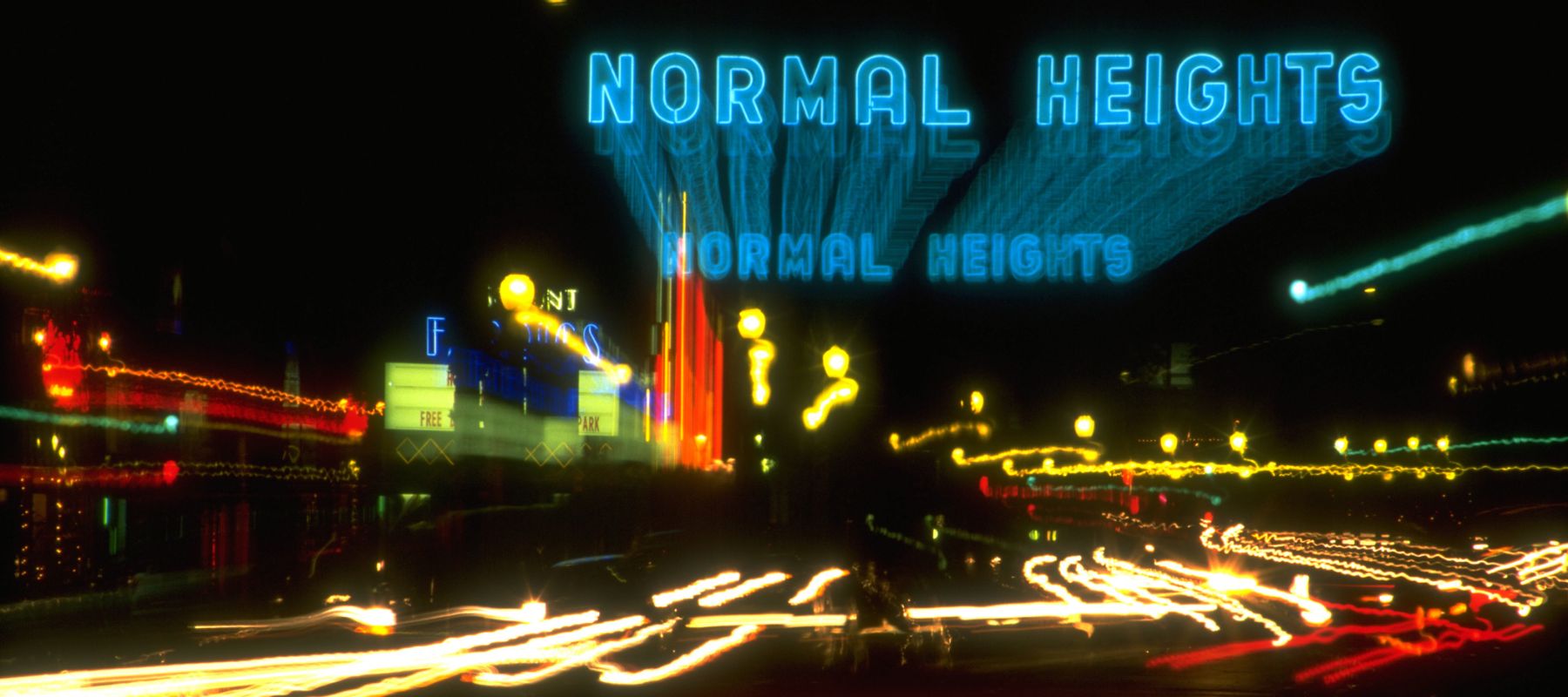 A blurred night shot of a city street features neon blue 