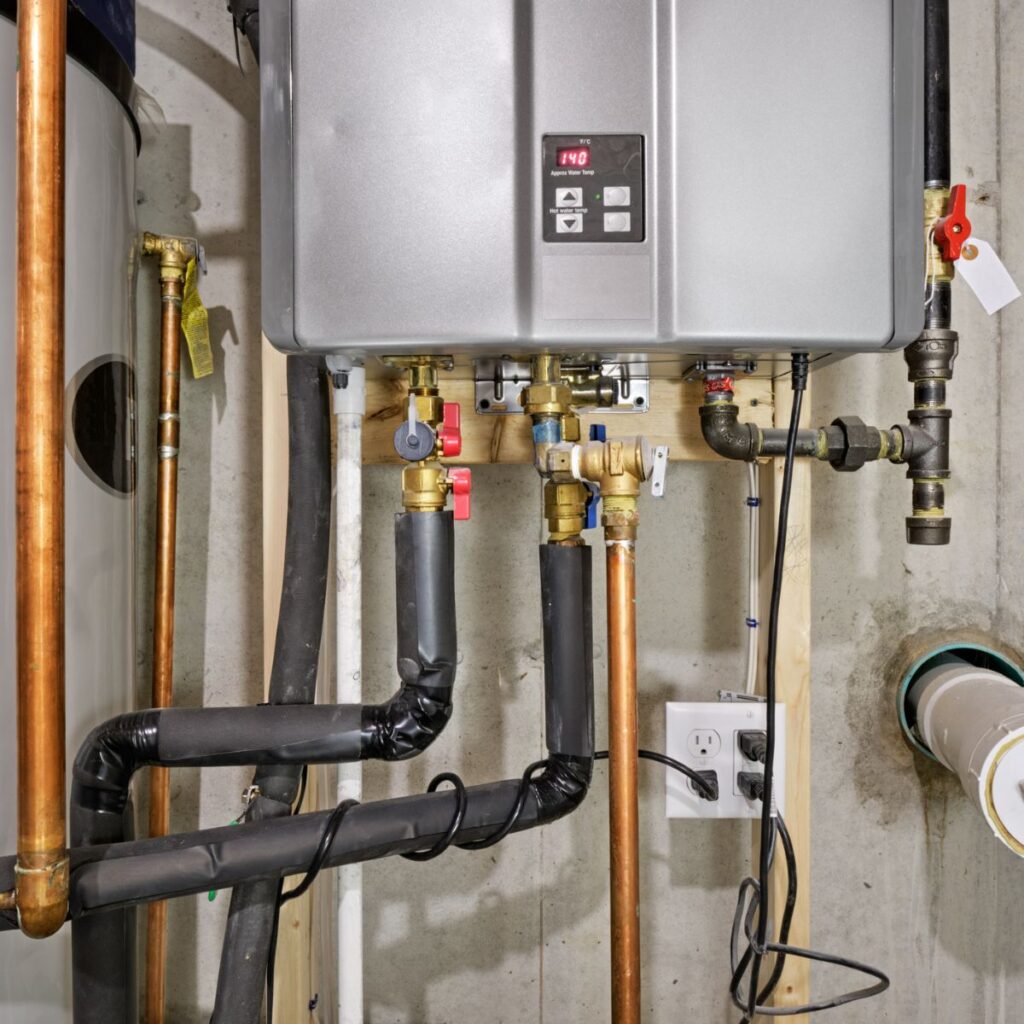 Installed tankless water heater with pipes and valves mounted on a basement wall