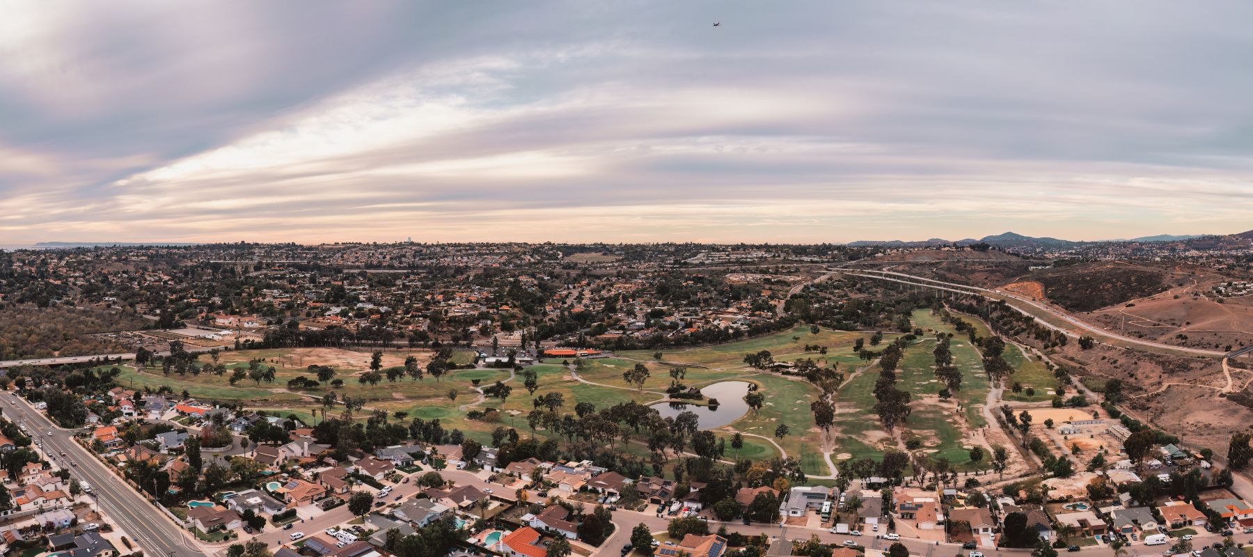Aerial view of Bonita, California with residential neighborhoods, a golf course, and surrounding hills under a cloudy sky