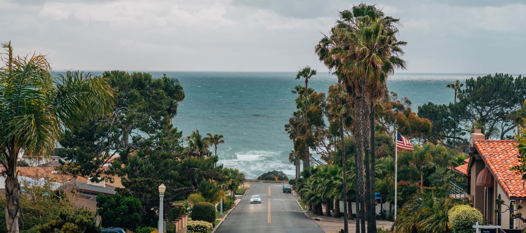Scenic view of a coastal street in Point Loma leading to the ocean lined with palm trees